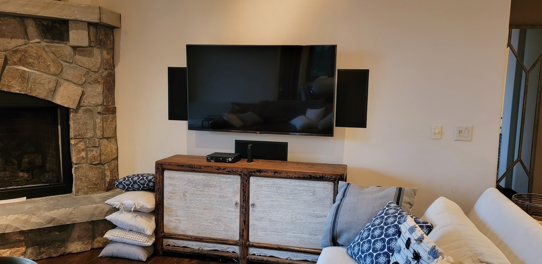 A living room home theater setup with a wall-mounted screen and speakers.